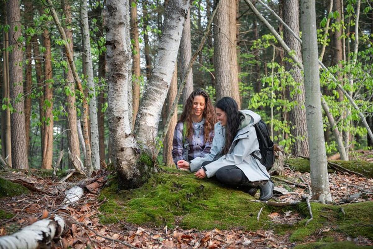 two women sitting on the ground in the woods
