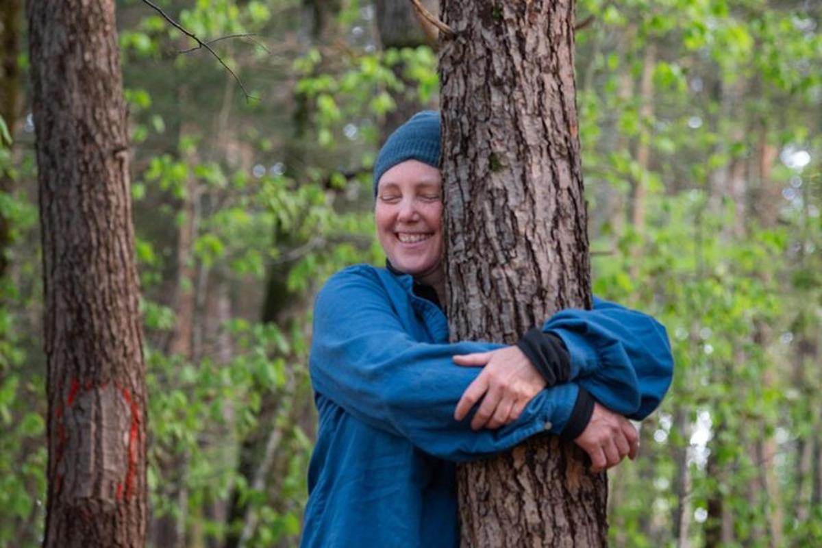 a woman hugging a tree in a forest