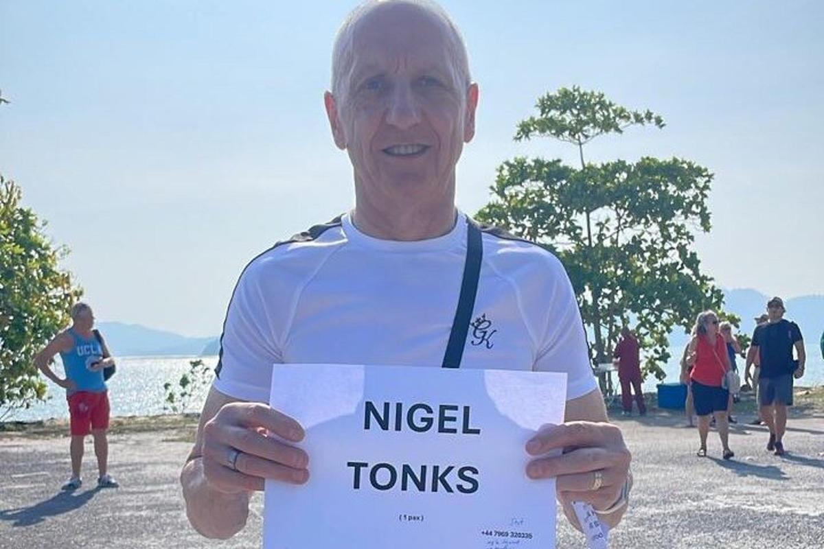 Maður heldur á skilti sem á stendur Nigel Tours
