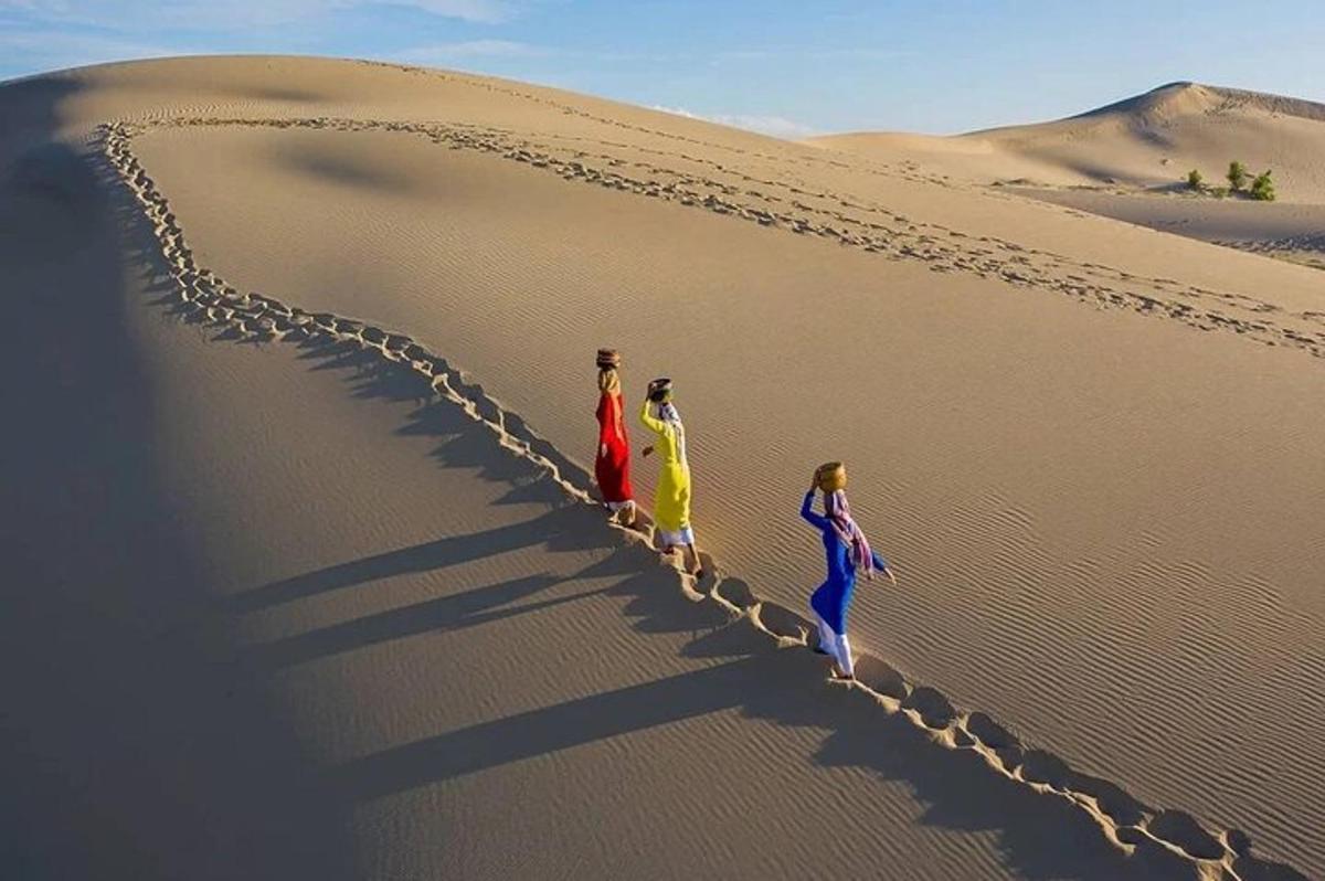 tre persone che camminano su una duna di sabbia nel deserto