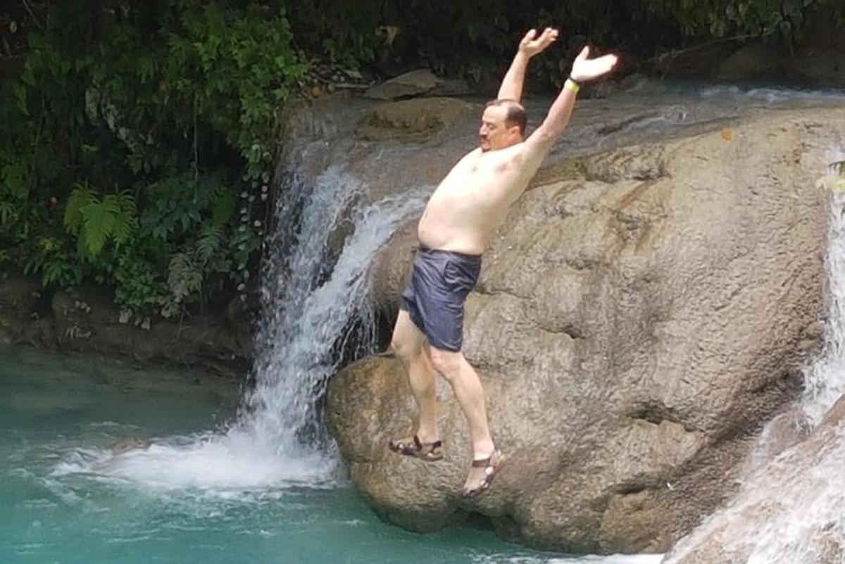 a man standing on a rock in front of a waterfall