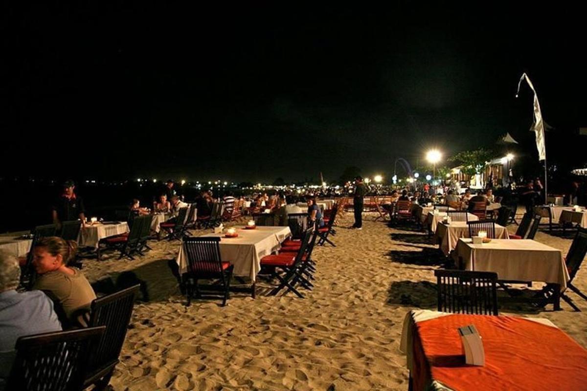 a group of tables and chairs on a beach at night
