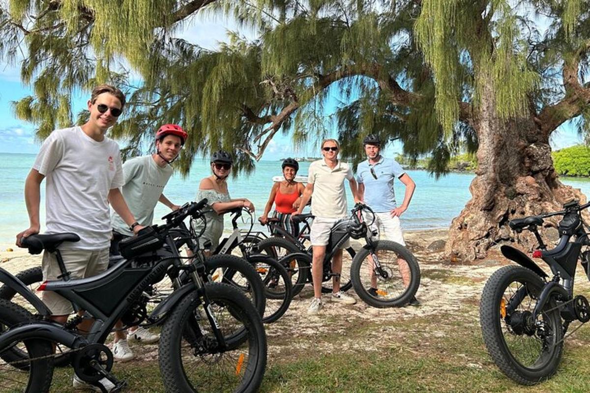 Un grupo de personas de pie junto a sus bicicletas en la playa.