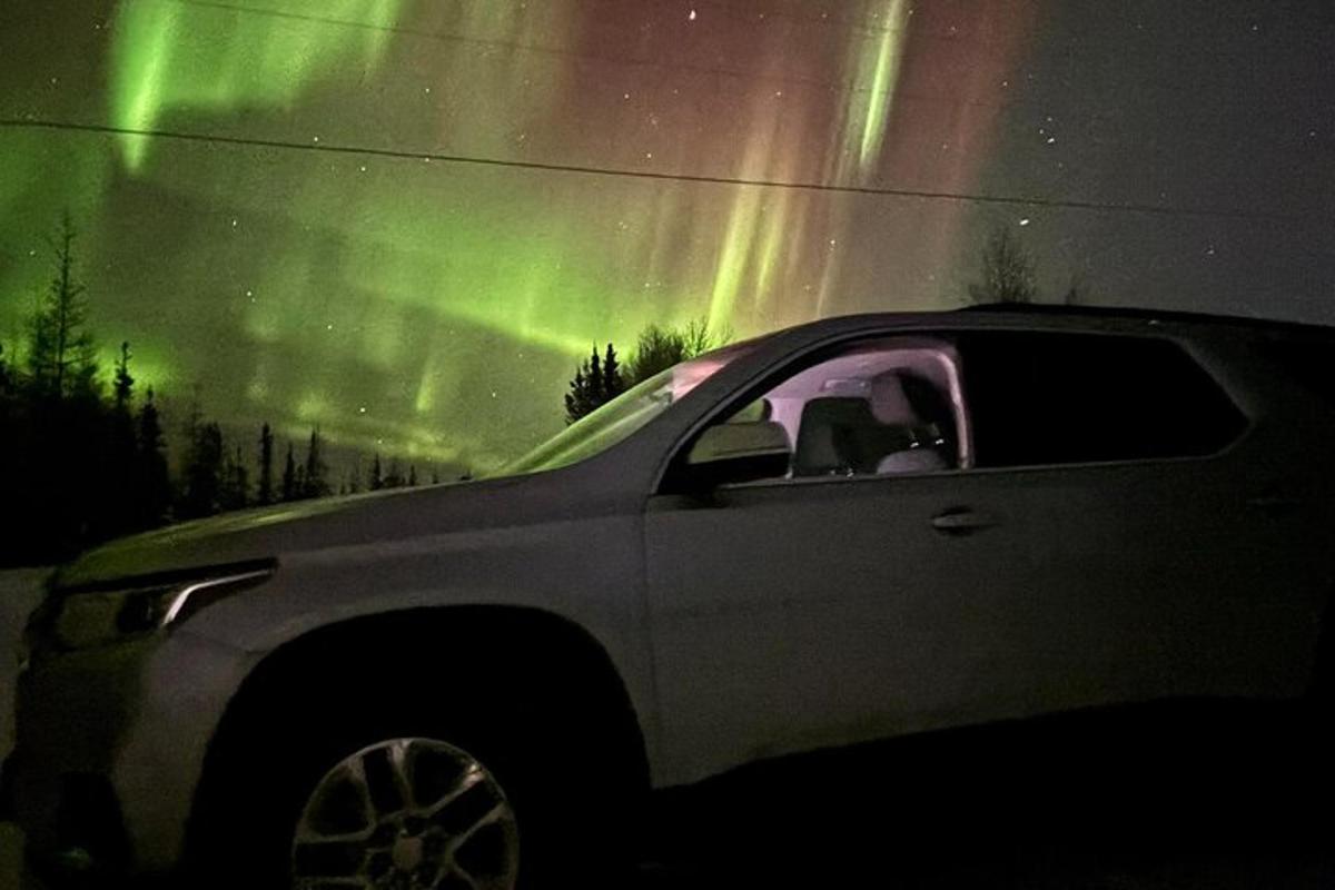 un cotxe està aparcat davant de l'aurora boreal