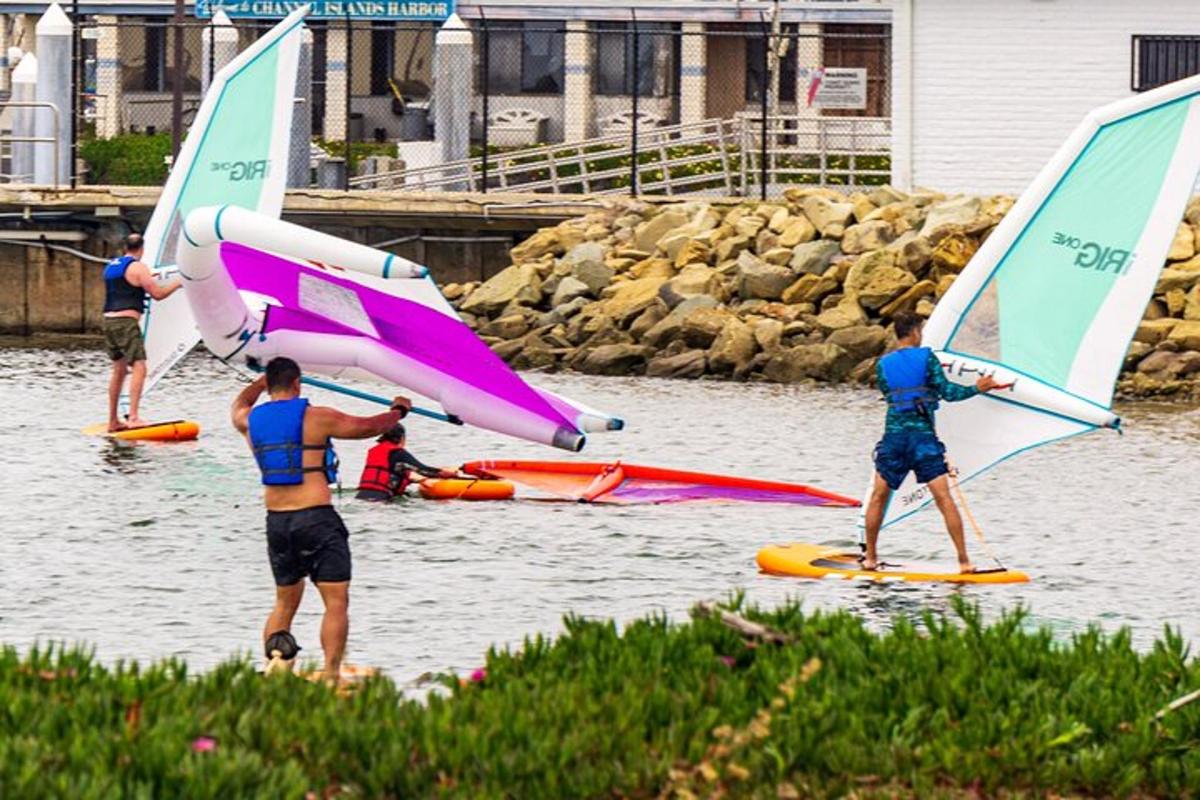 a group of people on the water with sailboards