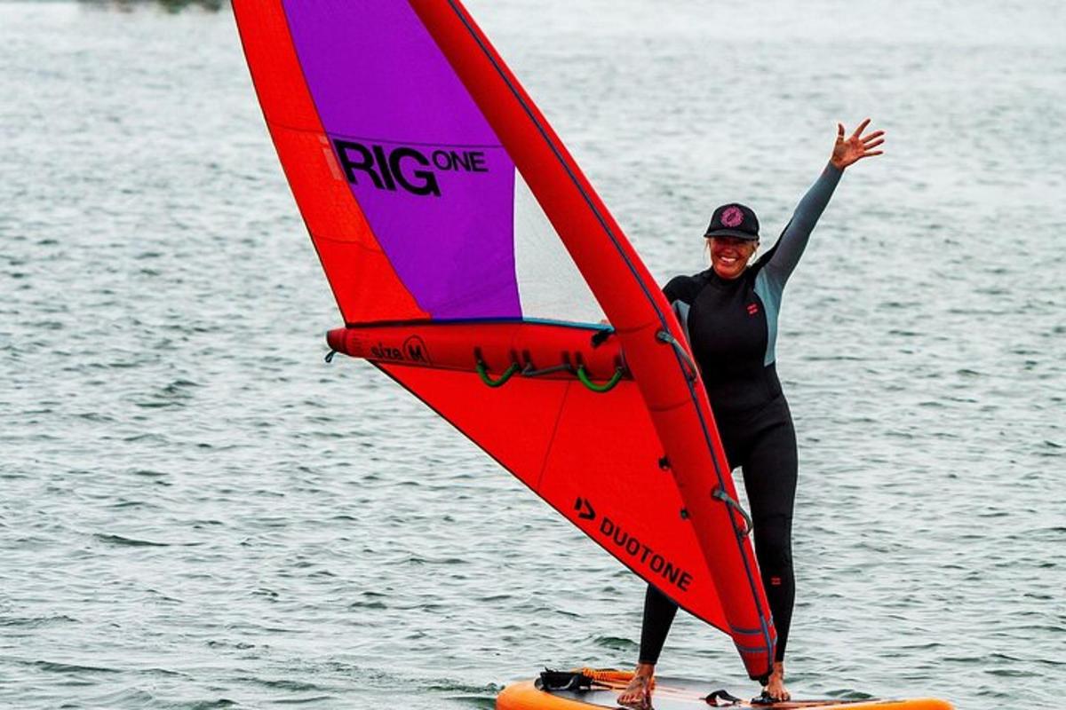 a man standing on a surfboard with a sail
