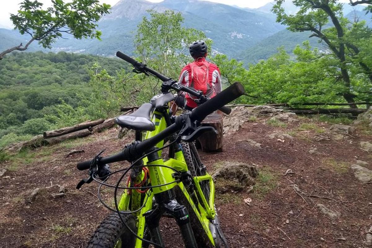 un home dret al costat d'una bicicleta en un turó