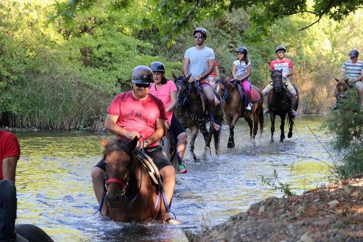 eine Gruppe von Menschen reitet auf Pferden durch einen Fluss