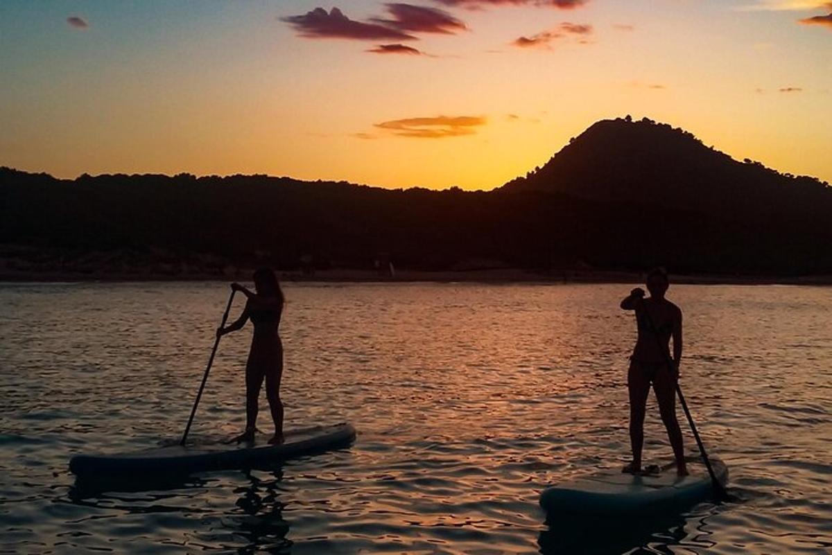 dva lidé na paddleboardech ve vodě při západu slunce