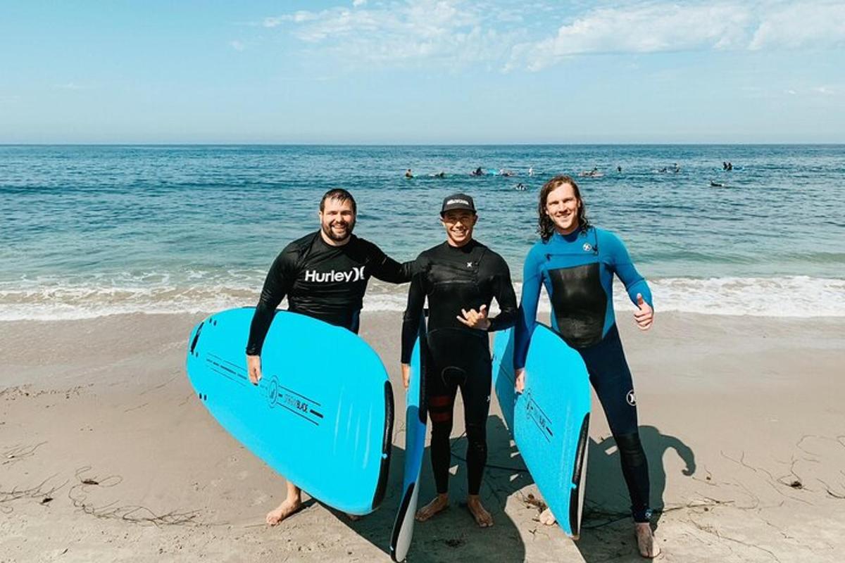 un gruppo di tre persone in piedi sulla spiaggia con le tavole da surf