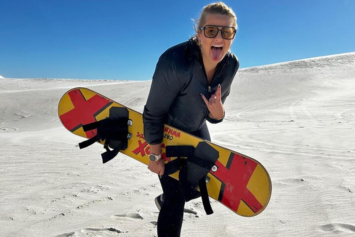 žena stojící na pláži a držící snowboard