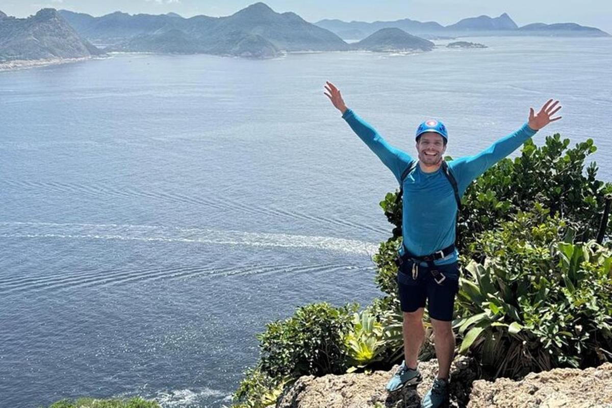 um homem em pé no topo de uma montanha com os braços para cima