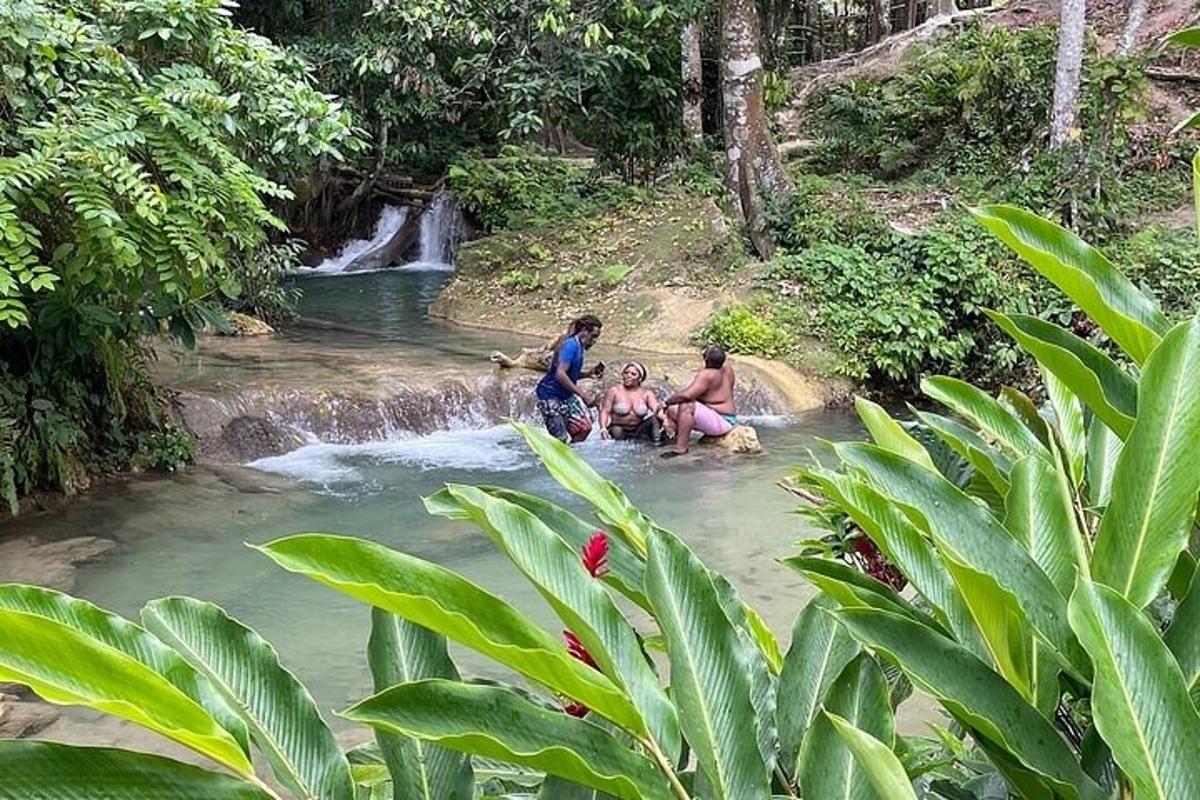 tiga orang duduk di air dekat air terjun