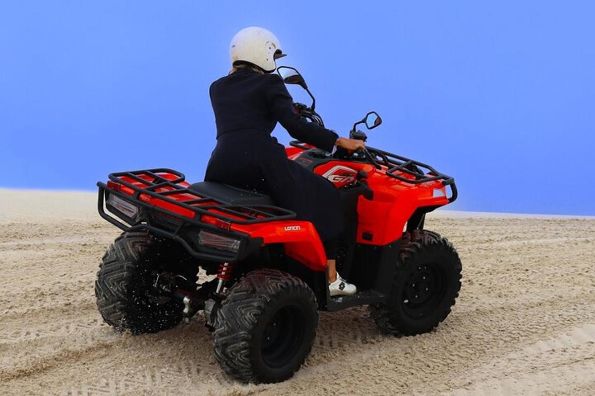 egy személy egy piros ATV-vel a homokban