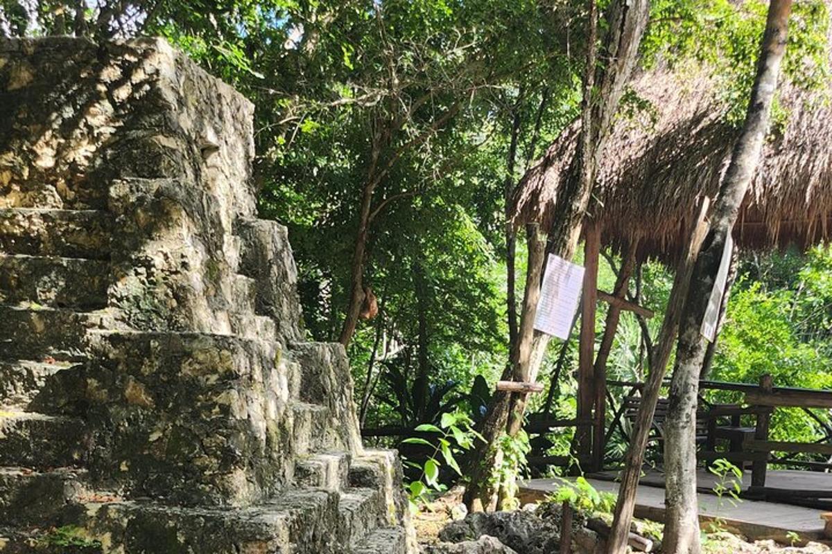 Un edificio de piedra con una choza de paja y árboles.