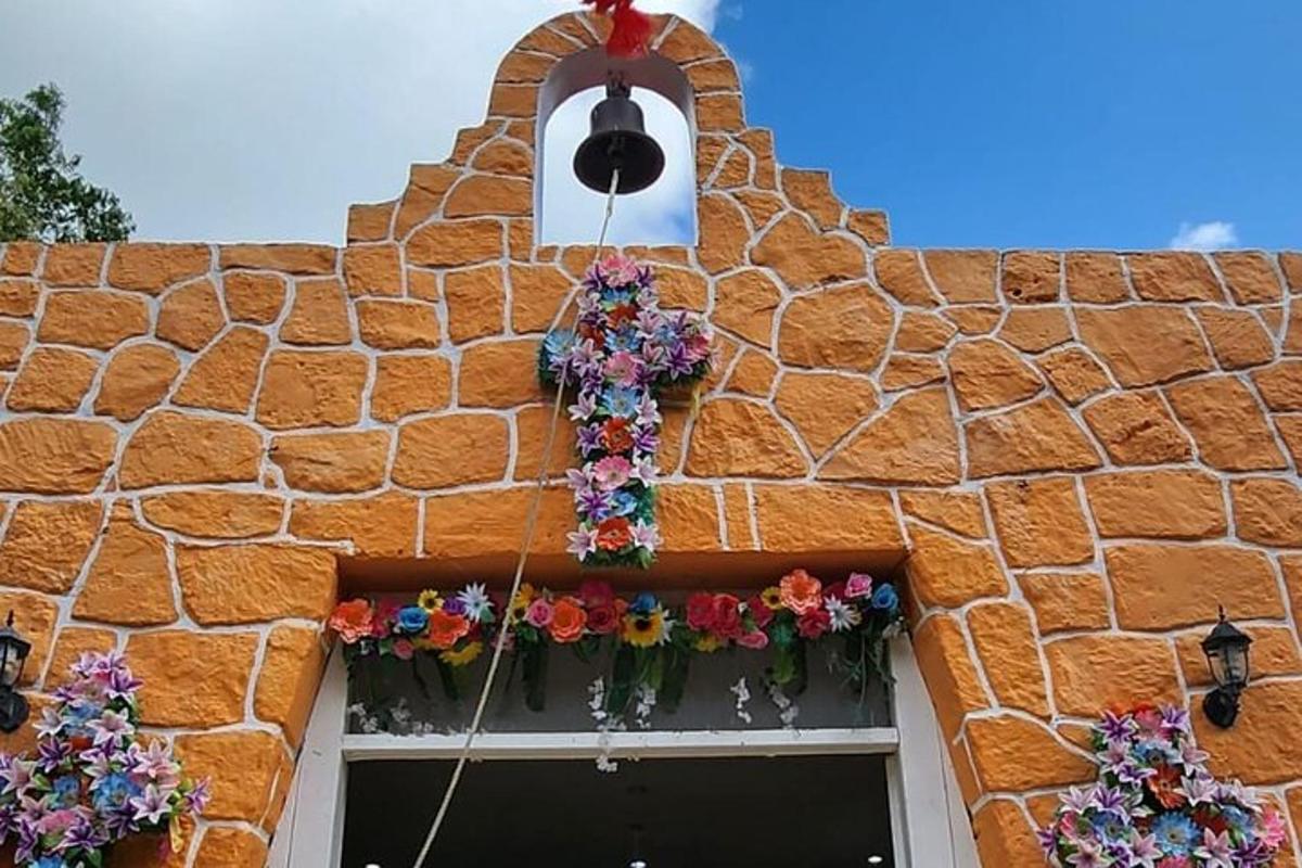 isang gusaling may pader na bato na may mga bulaklak at kampana