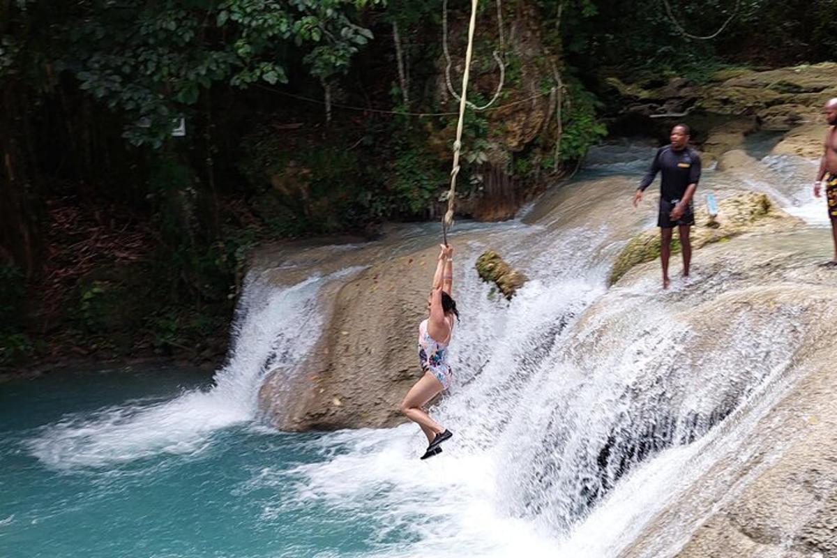 uma pessoa está pendurada em uma corda sobre uma cachoeira