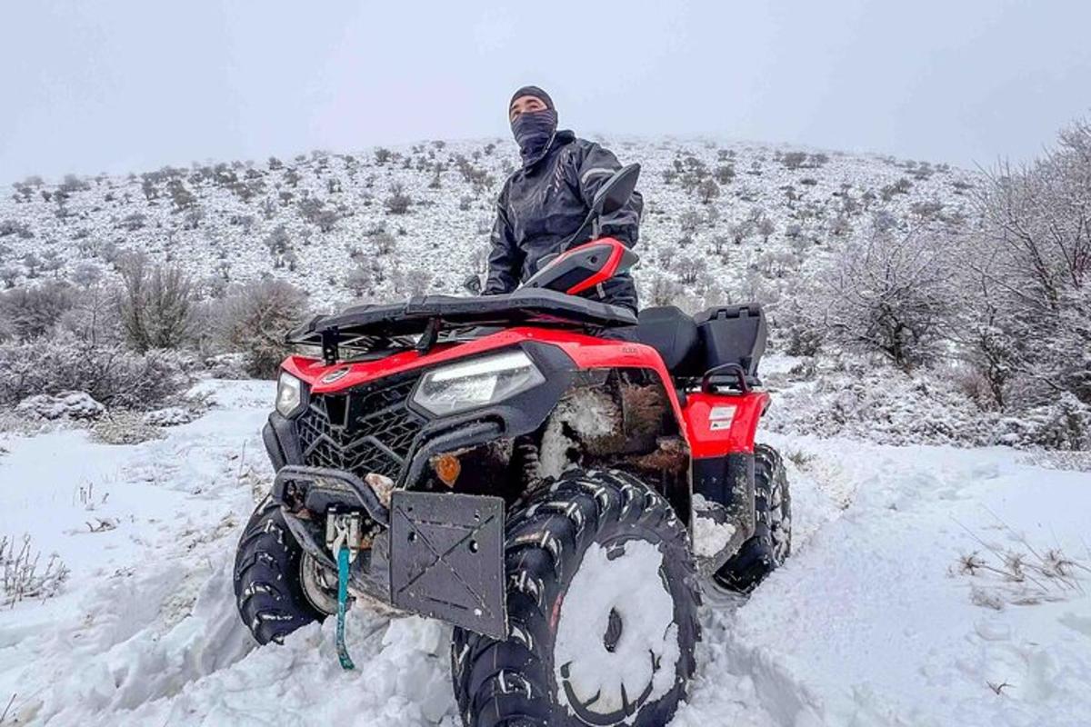 seorang lelaki berdiri di atas atv di dalam salji