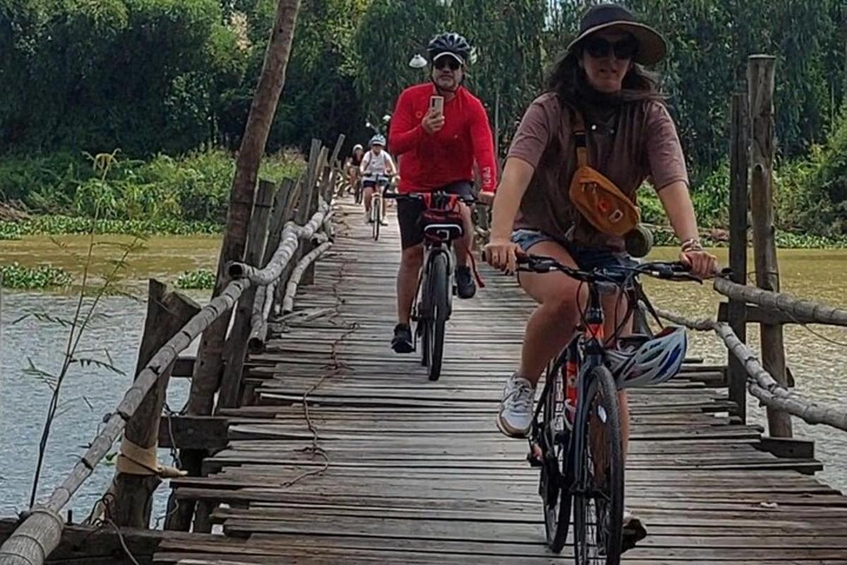 skupina lidí jedoucích na kolech přes dřevěný most