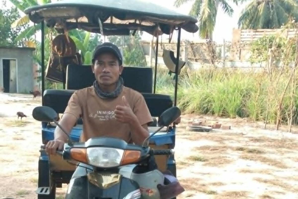 ชายคนหนึ่งนั่งอยู่บนมอเตอร์ไซค์พร้อมรถกอล์ฟ