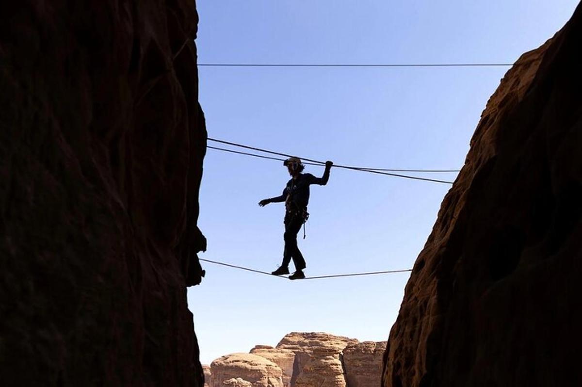 a man walking on a rope between two cliffs