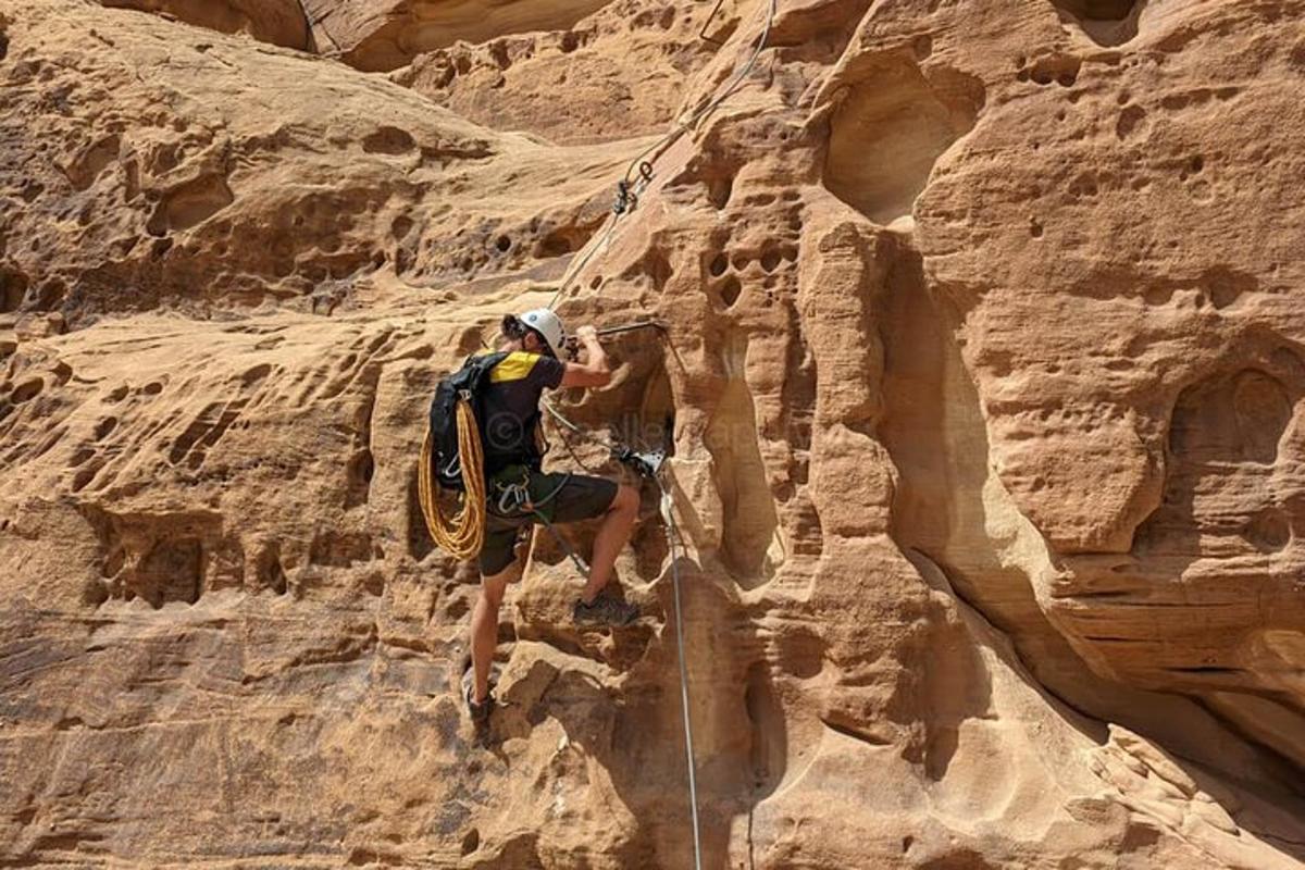a man climbing on a rock wall in a canyon