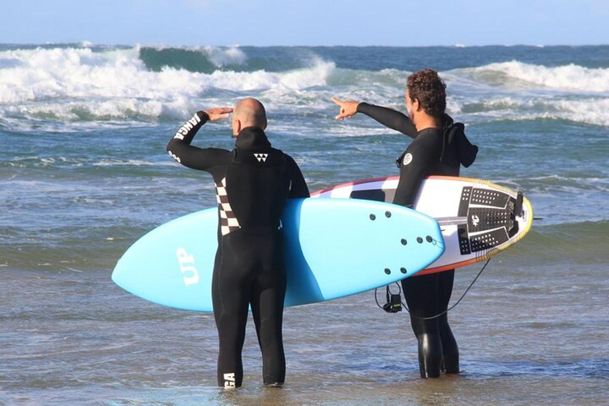 dwie osoby stojące w oceanie z deskami surfingowymi