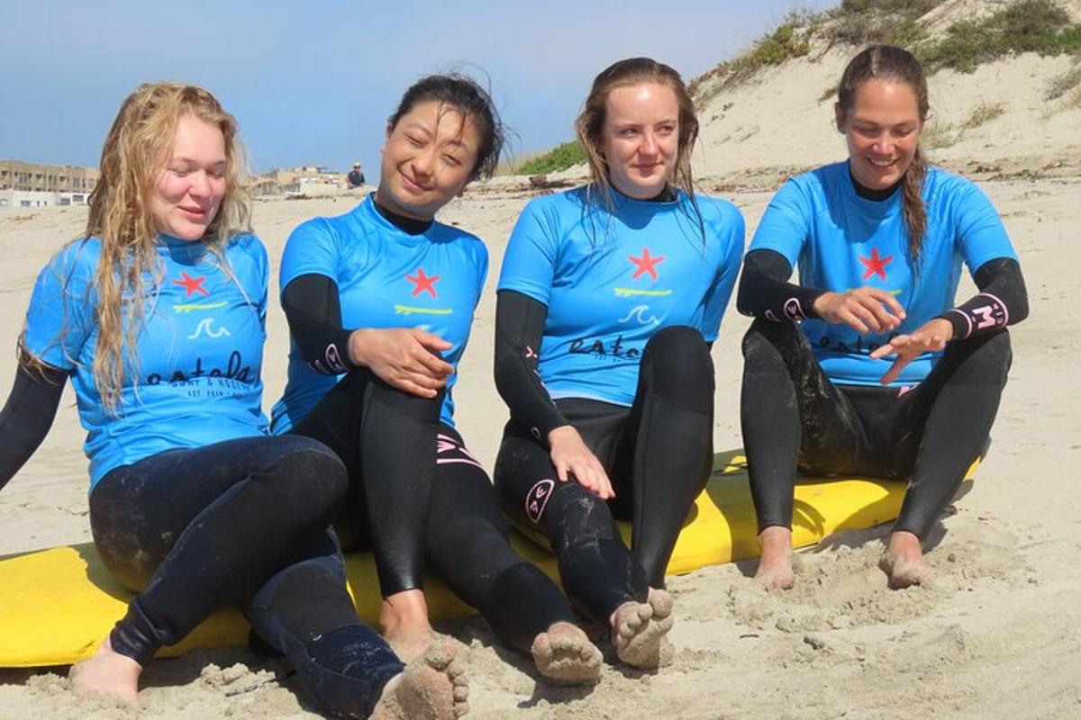 Čtyři lidé sedí na surfu na pláži