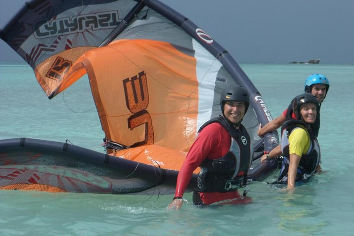 Un grupo de personas en el agua con una vela de viento.