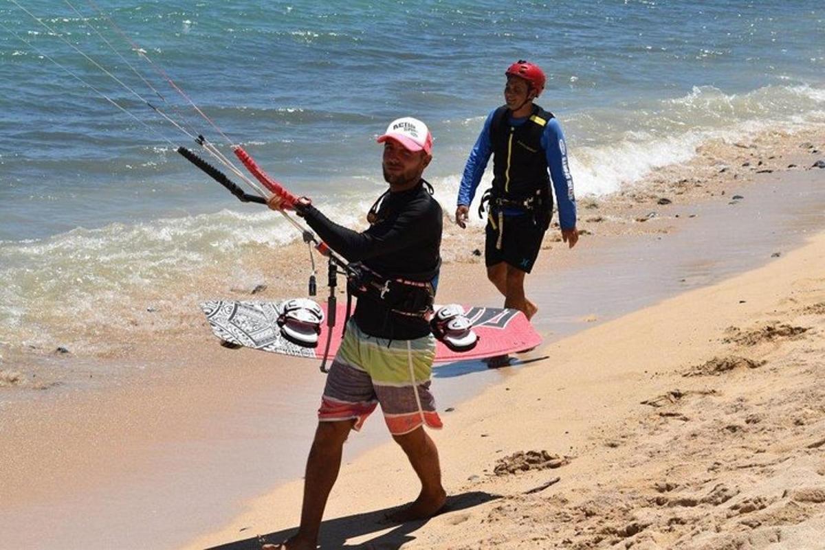 dva muškarca stoje na plaži držeći zmaja