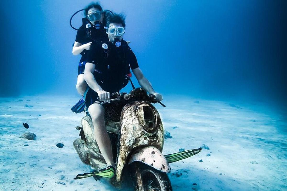 two people sitting on a scooter in the ocean