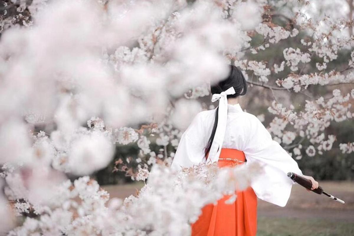 isang taong nakasuot ng graduation hat at orange skirt na nakatayo sa tabi ng cherry tree