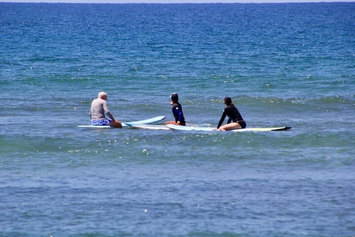 tre persone sedute su tavole da surf nell'oceano