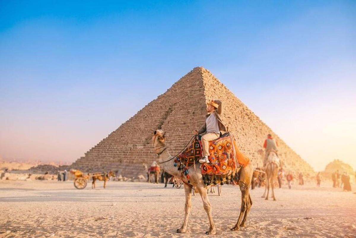 en kvinne som rir på en kamel foran pyramidene