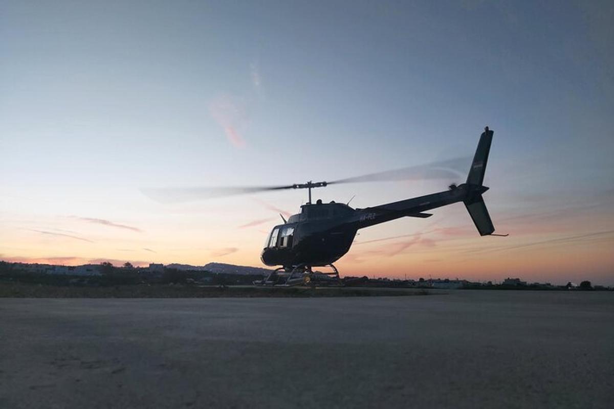 helikopter sedi na vzletno-pristajalni stezi ob sončnem zahodu