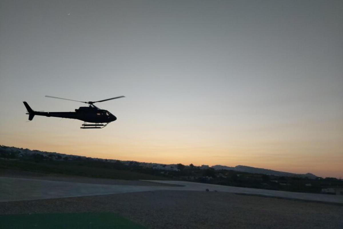 helikopteri lentää kiitotien yli auringonlaskun aikaan