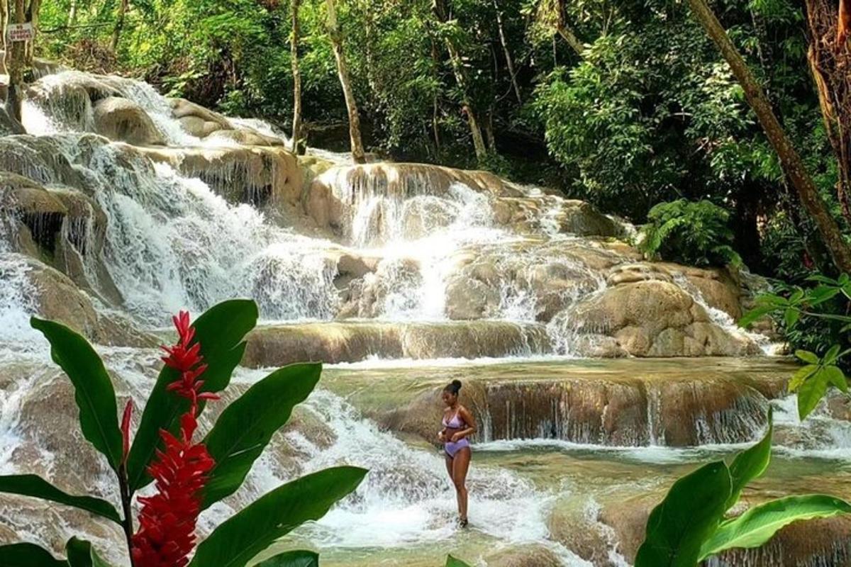 uma mulher parada na água em frente a uma cachoeira