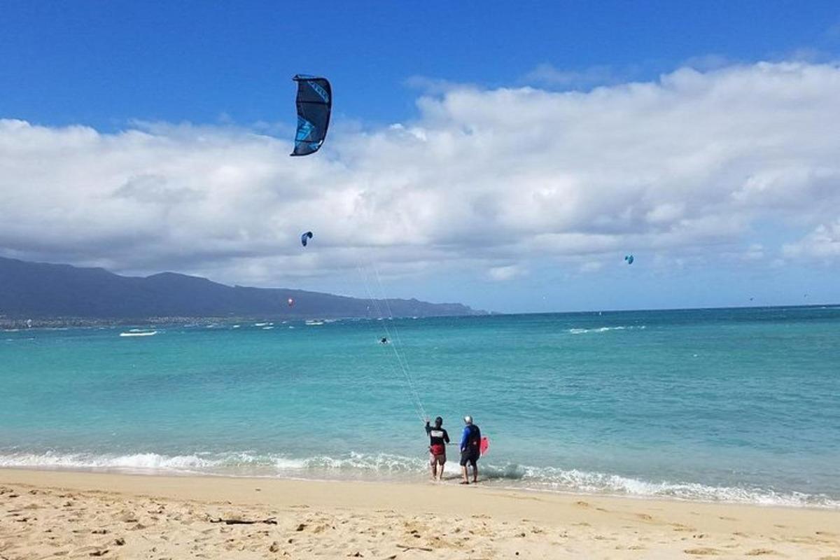 dues persones dempeus a la platja fent volar un estel