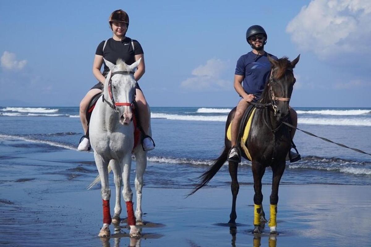 two people are riding horses on the beach