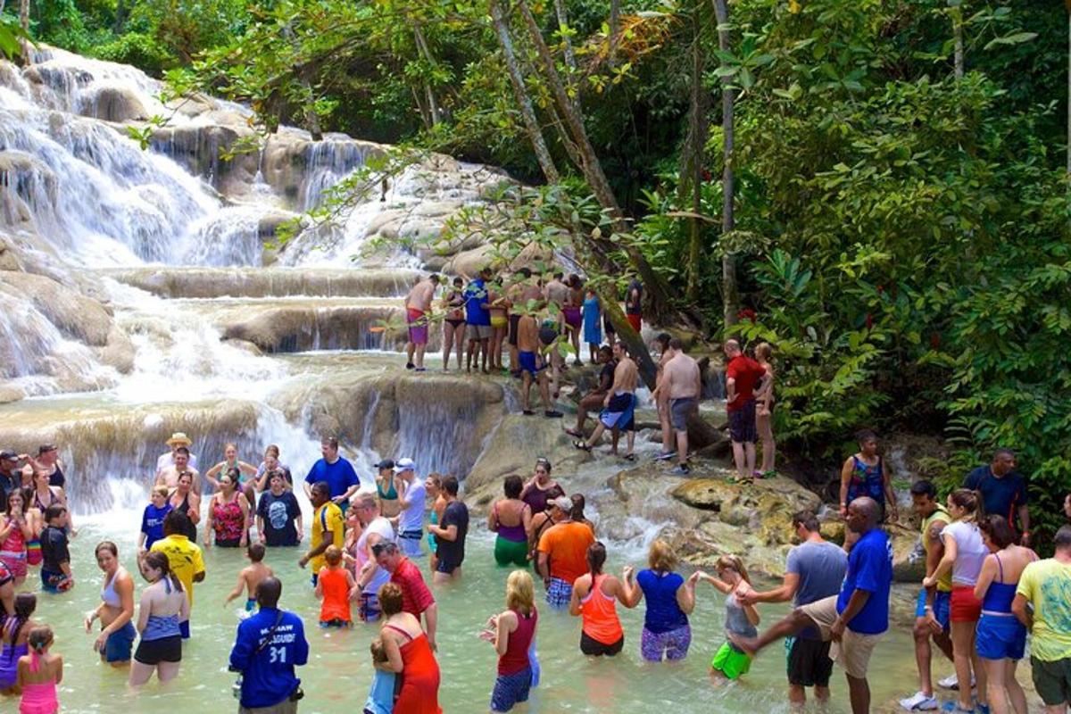 sekumpulan orang berdiri di dalam air di air terjun