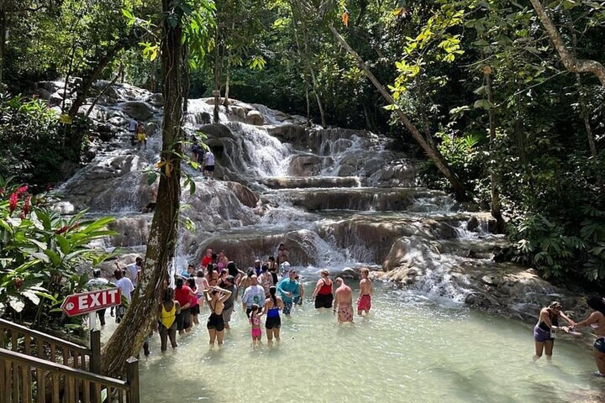 sekumpulan orang berdiri di dalam air berhampiran air terjun