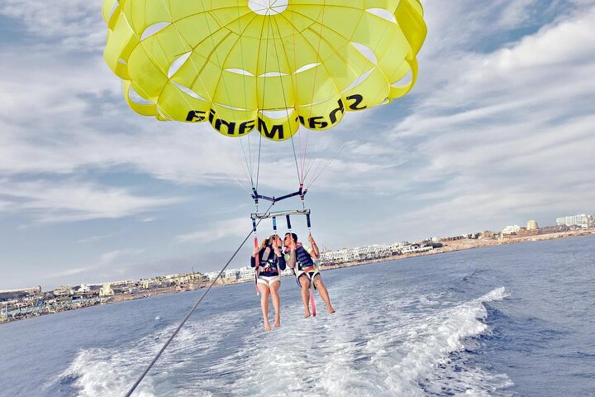 a group of people standing on the beach with a parachute