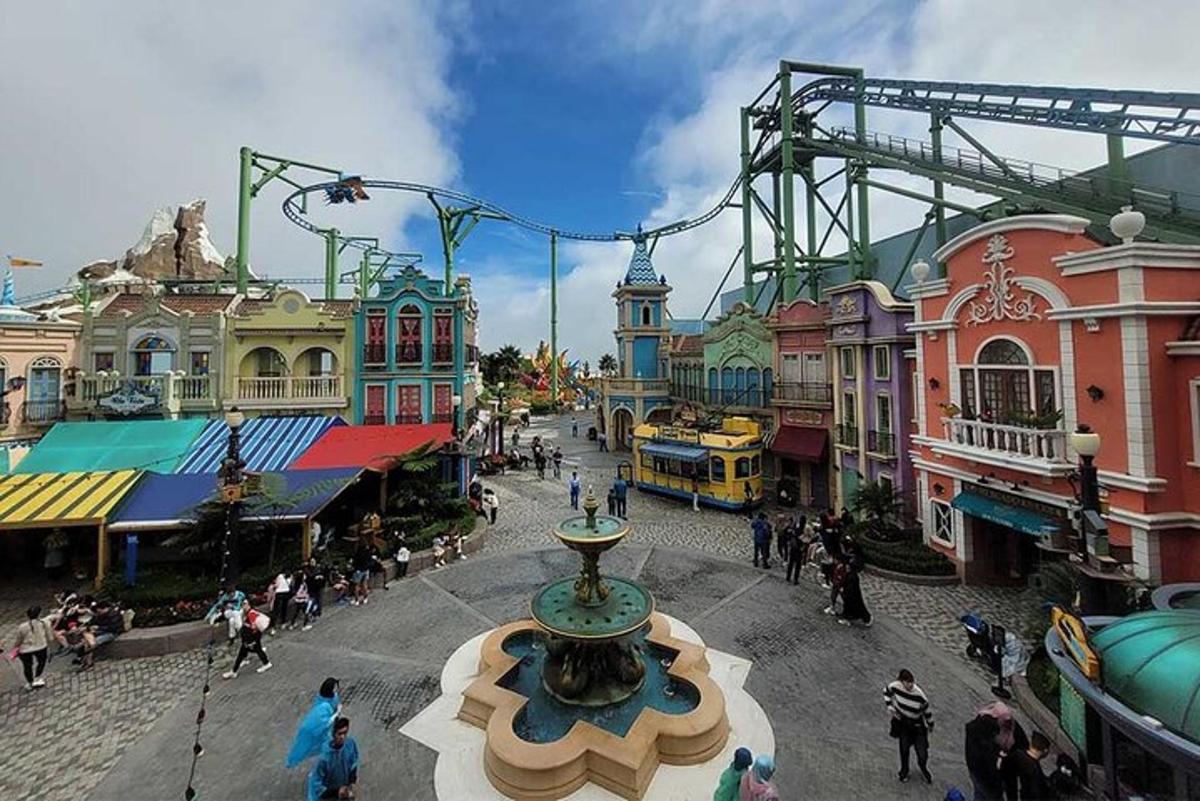 an amusement park with a roller coaster and a fountain