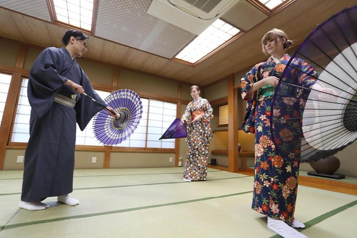 drei Frauen in Kimonos stehen in einem Raum mit Regenschirmen