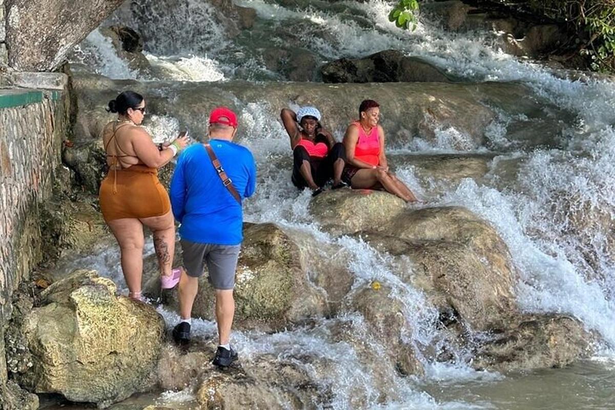 sekumpulan orang duduk di atas batu di air terjun