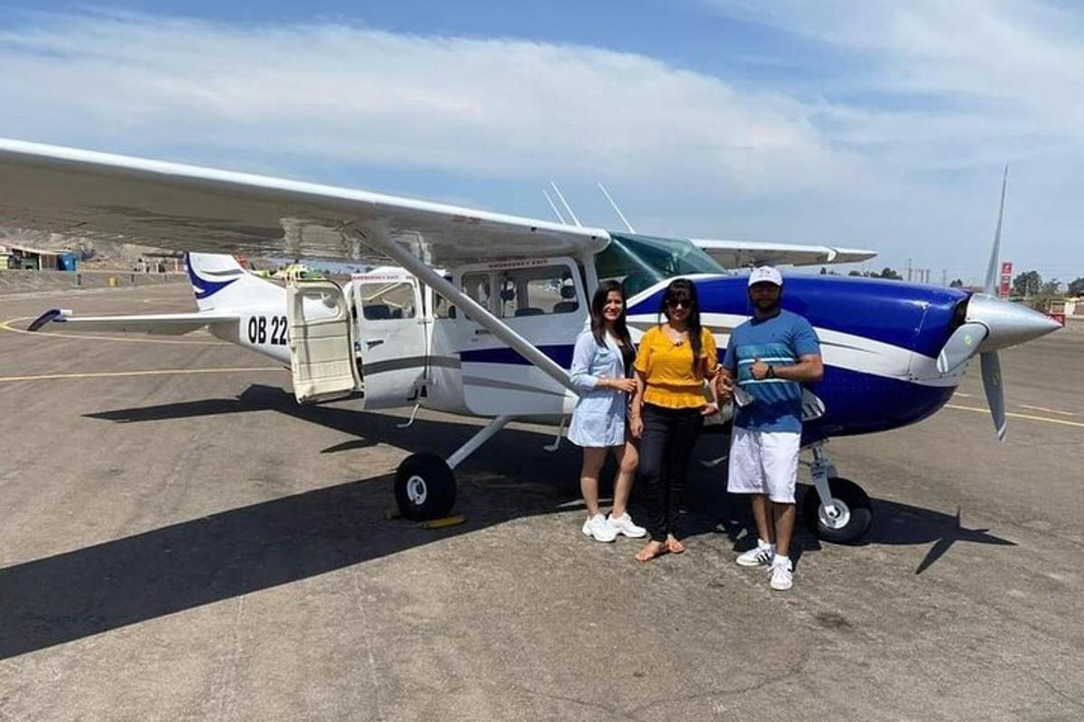 three people standing in front of a small plane