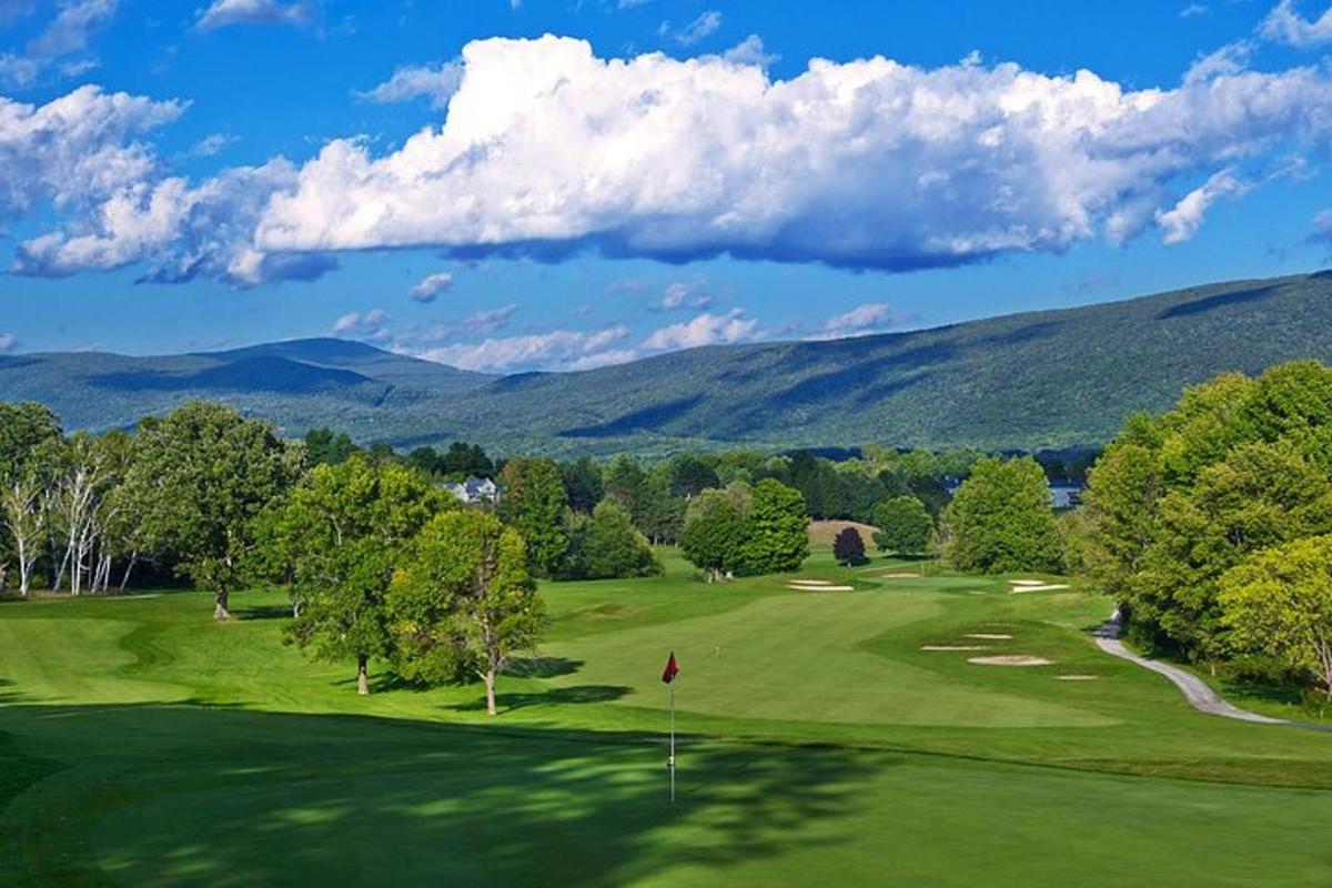 Blick auf einen Golfplatz mit Bergen im Hintergrund