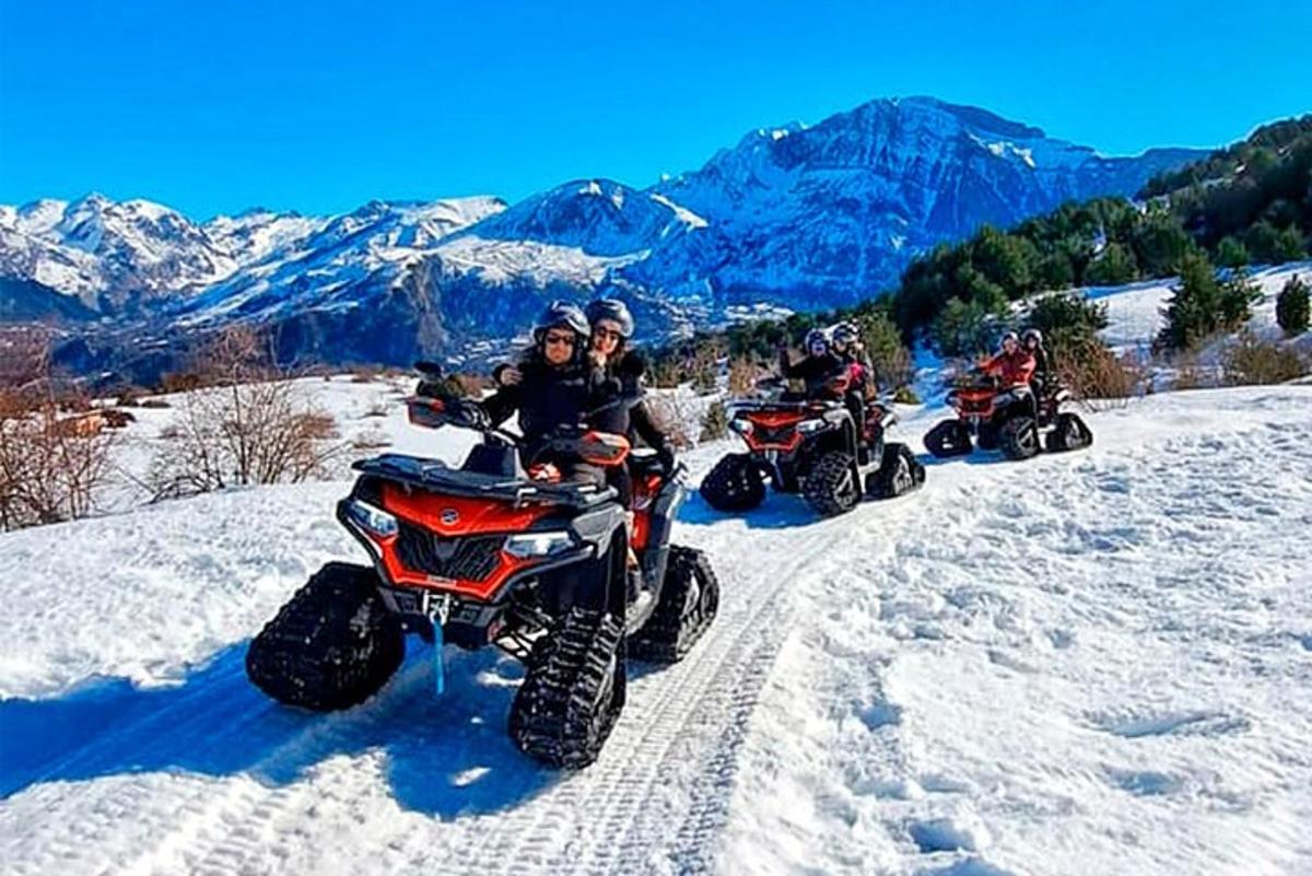 eine Gruppe von Menschen, die auf Geländefahrzeugen im Schnee fahren