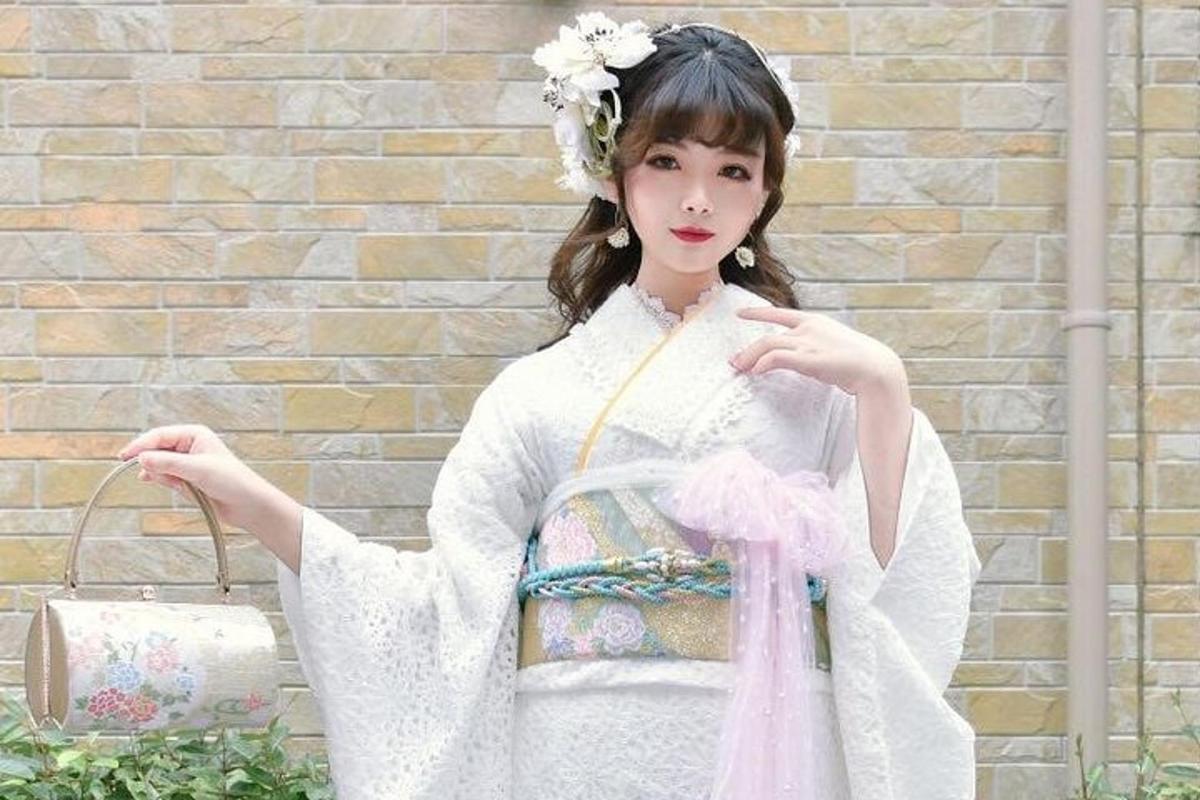 Una mujer con un vestido blanco sosteniendo un bolso