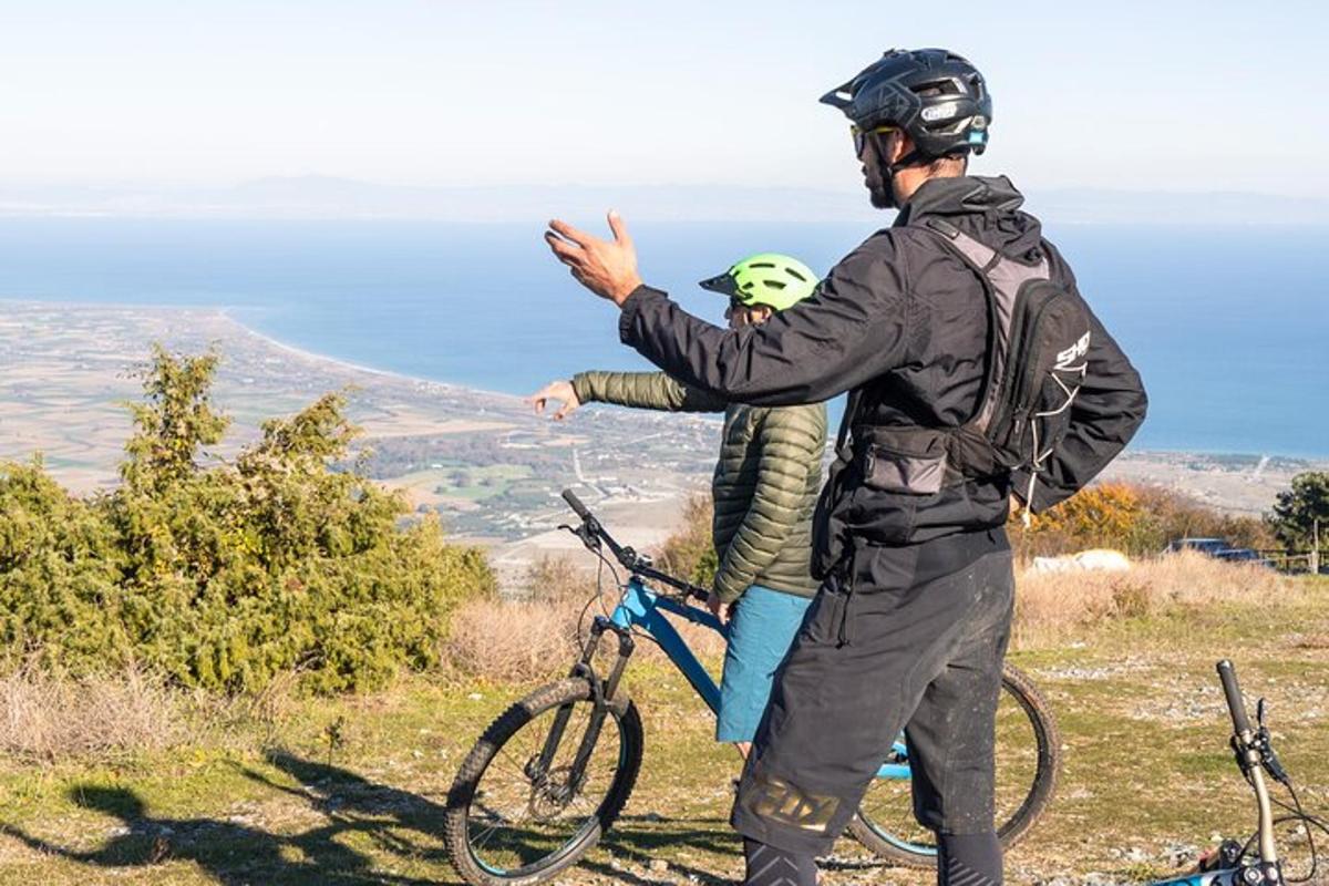 Un hombre parado en una colina con una bicicleta